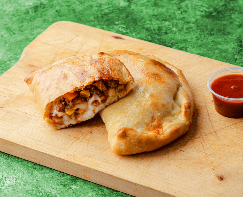 Calzone with dipping sauce on a wooden platter