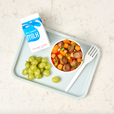 Sweet potato hash bowl with green grapes and a carton of milk on a light blue tray