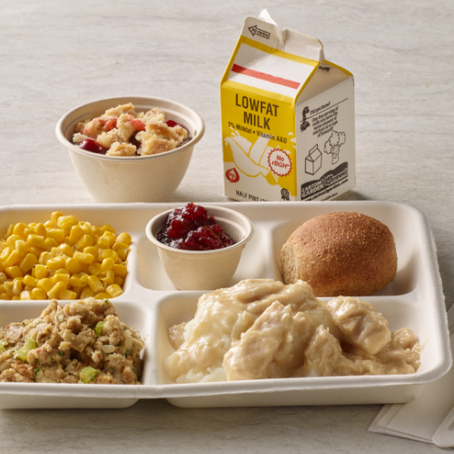 Turkey and gravy on a lunch tray with stuffing, corn, cranberry sauce and a dinner roll