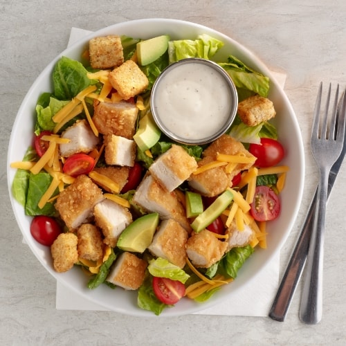 Salad topped with pieces of dill turkey patty